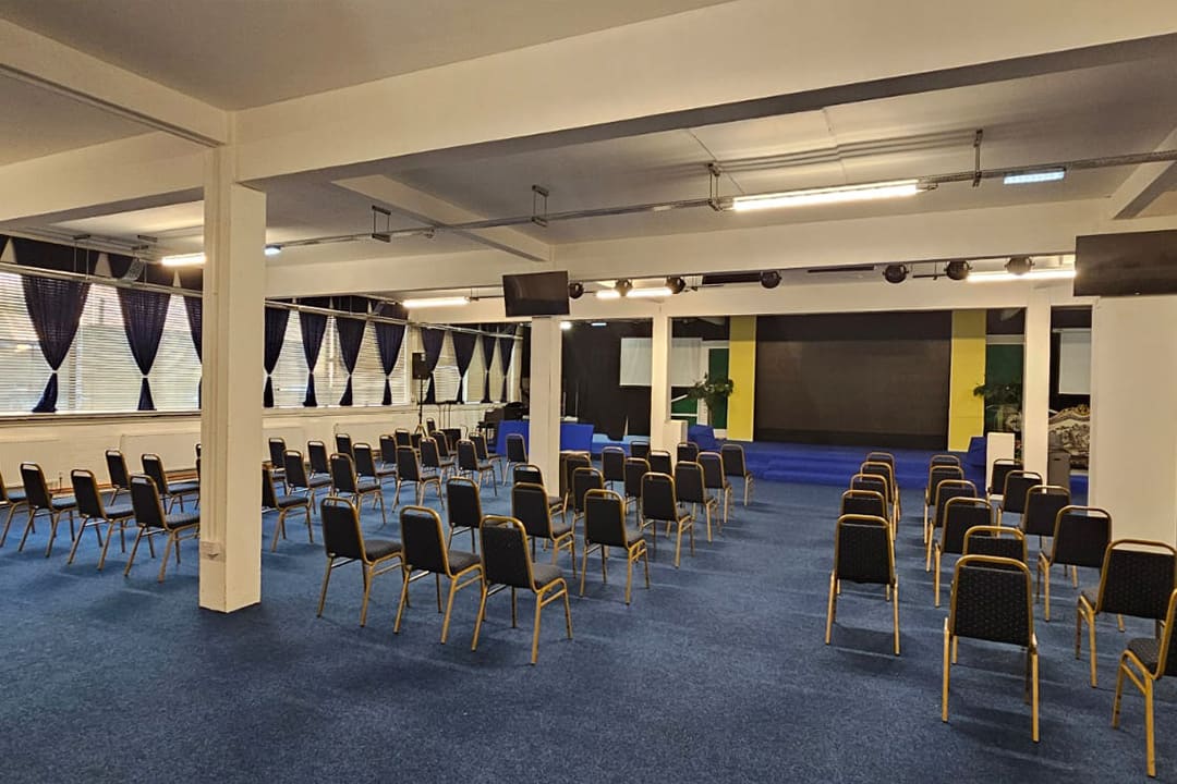 A wide view of the Grand Conference Hall with rows of chairs and draped windows.